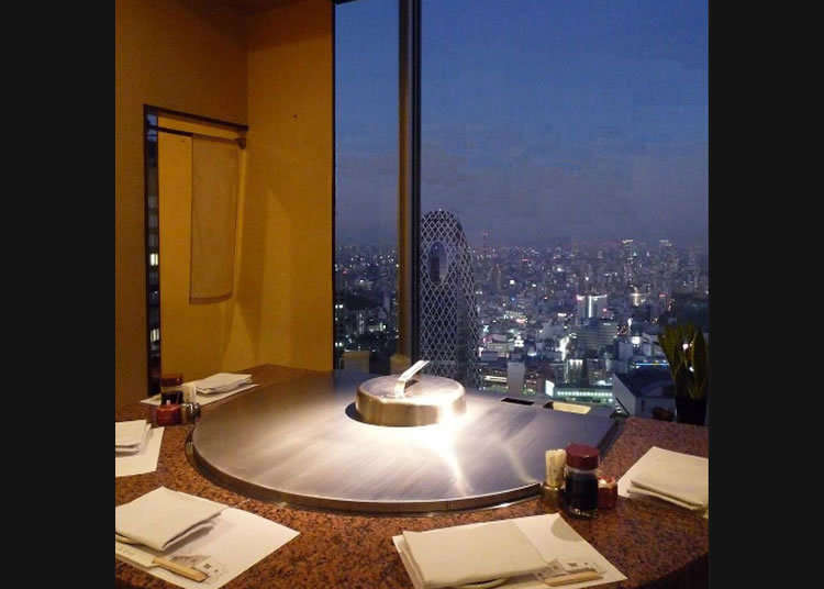 Pemandangan malam yang terhampar di seluruh bagian jendela dan hidangan lezat teppan yaki.